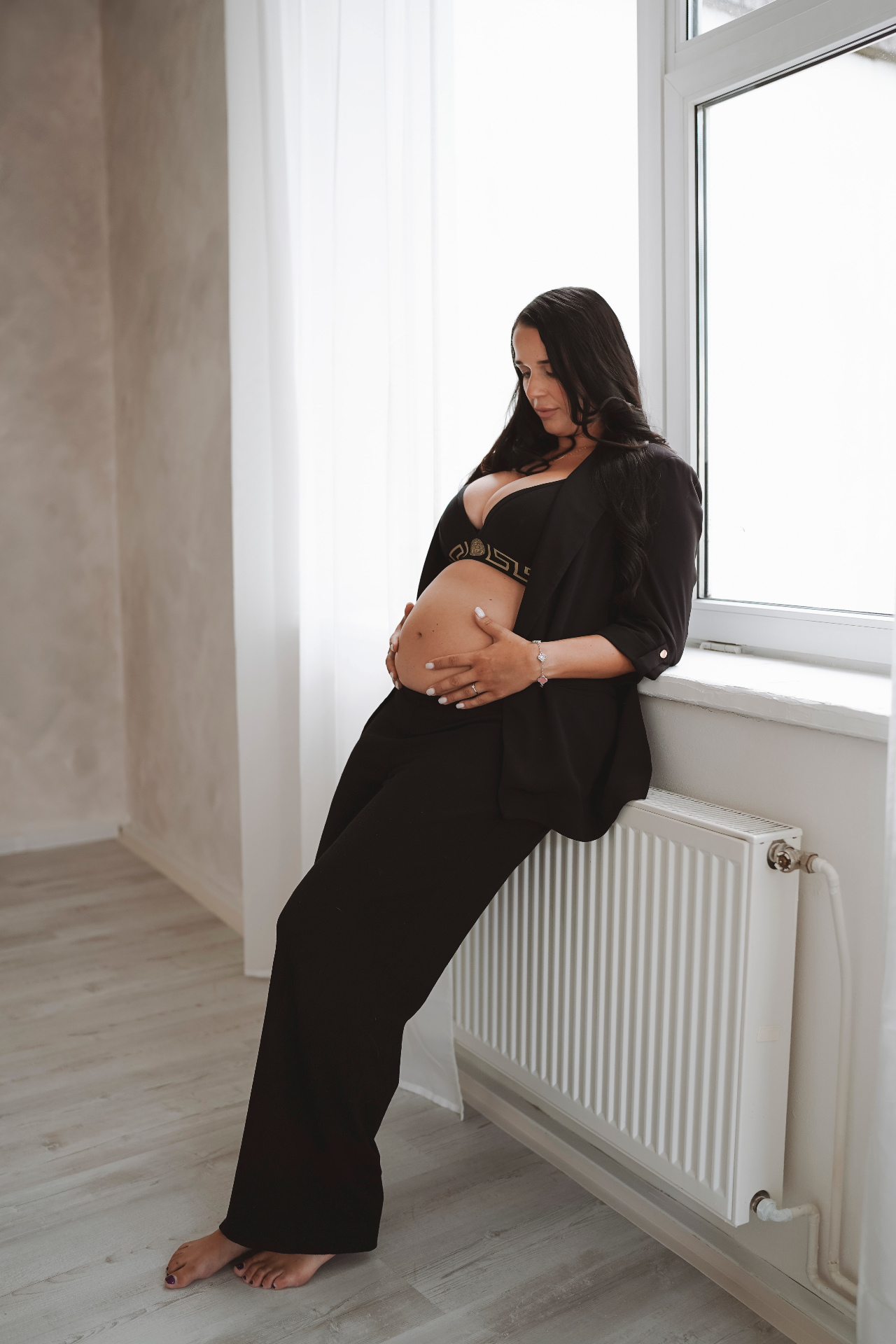 Těhotná žena u okna v černém outfitu
