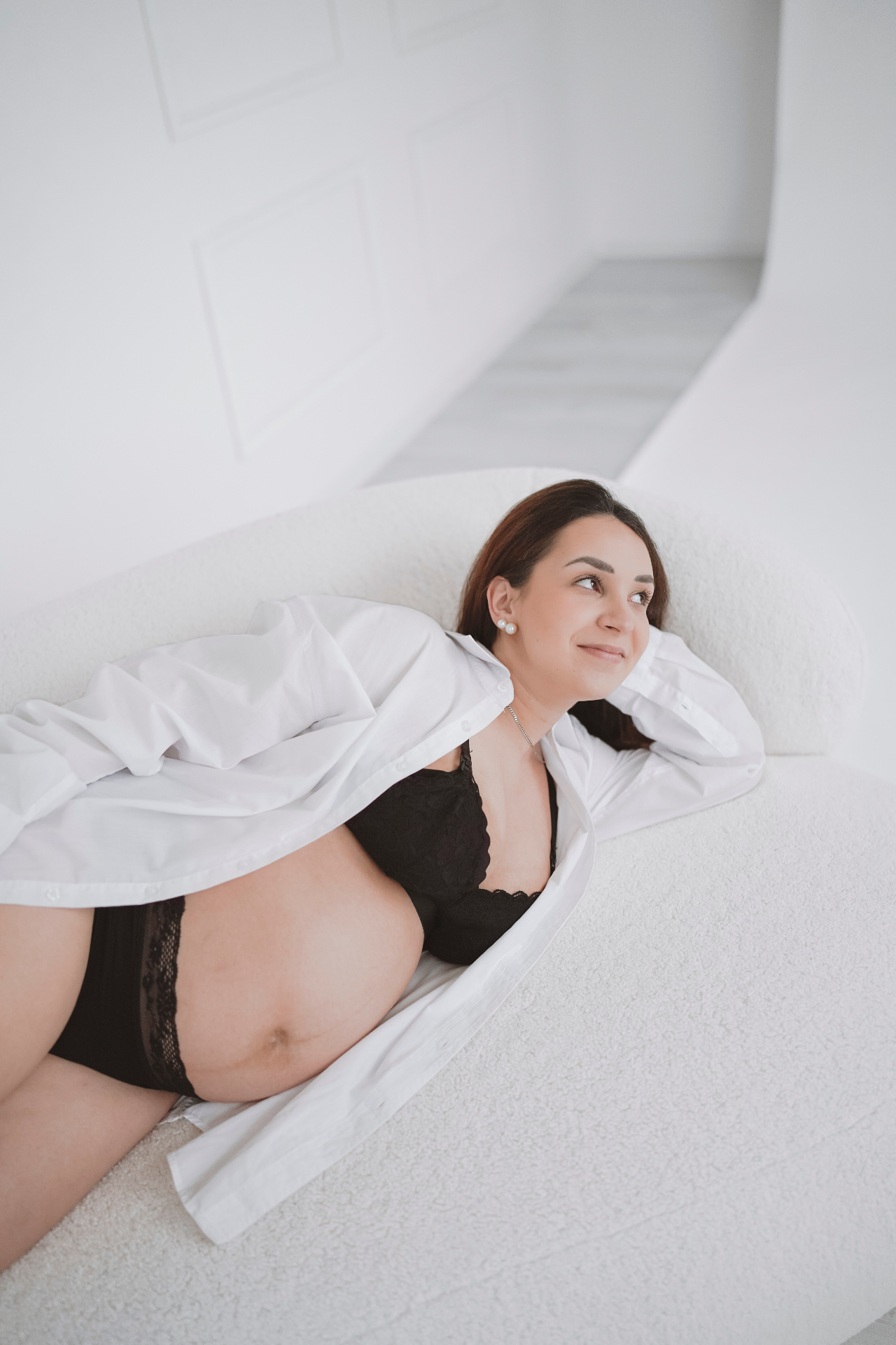 Těhotná žena v bílé košili v jasném ateliéru